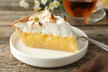 Piece of delicious pie with browned meringue on wooden table, closeup
