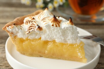 Piece of delicious pie with browned meringue on wooden table, closeup