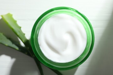 Cream and aloe leaves on white wooden background, flat lay