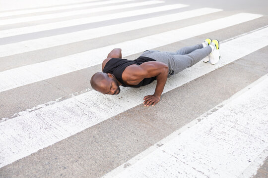 Fitness cuban man doing push ups on an urban crosswalk