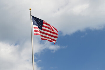 Close up full frame of United States of America flag flying in the wind with blue sky background