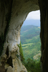 A stunning view from inside a cave overlooking lush green hills and forests in the north of Spain.