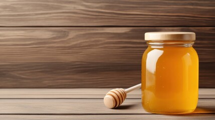 Glass jar filled with golden honey on wooden background with honey dipper beside jar for kitchen decor