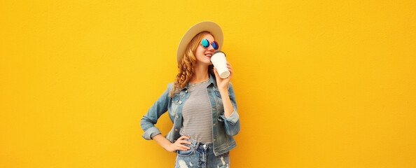Beautiful stylish happy young woman with cup coffee wearing summer hat posing on yellow background
