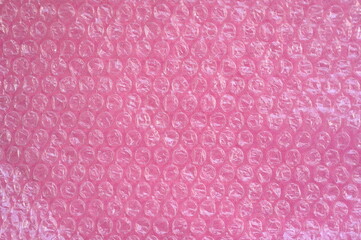 Close-up of the texture of pink bubble wrap as a background. Transparent air-filled pockets create...