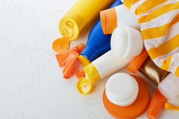Used plastic colorful containers and lotions placed at random alongside a colorful beach bag on a...