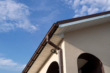 House with brown guttering installed along the edge of the roof