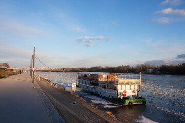 Stojąca barka przy brzegu Wisły, kry lodowe, Toruń, Polska, Barge standing on the bank of the Vistula River, ice floes, Toruń, Poland