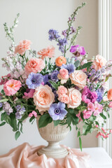 Luxurious floral arrangement with delicate pink and purple flowers with green branches in a tall ceramic vase