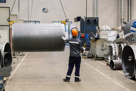 Pipe on overhead crane. Worker with remote control