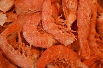 close-up of red tails of frozen shrimps, texture of frozen shrimps as background macro