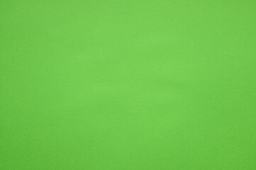 Close-up of the texture of green bubble wrap as a background. Transparent air-filled pockets create a structured, homogeneous pattern with a shiny, reflective surface. The bright green colour accentua