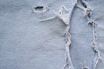 Distressed blue jeans fabric with frayed holes High-resolution close-up images of distressed denim with rips, tears, and frayed seams. Ideal for textile design, fashion branding, creative backgrounds,