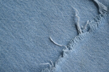 torn light grey denim surface, denim fringe , hole macro texture of blue denim, torn blue denim...