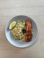 A plate of orzo with salmon and lemon.