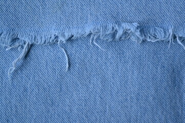 torn light grey denim surface, denim fringe , hole macro texture of blue denim, torn blue denim texture as background photo close up from above	
