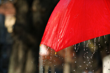 Open red umbrella under pouring rain outdoors, closeup