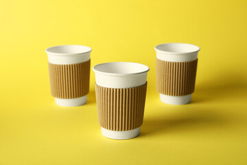 Paper cups on yellow background, selective focus. Mockup for design