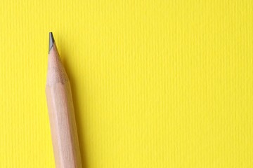 One pencil on yellow background, top view. Space for text