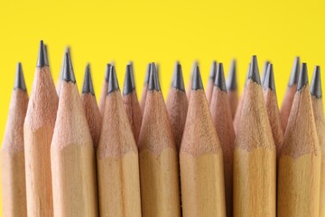 Many graphite pencils on yellow background, closeup