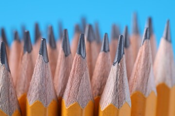 Many pencils on light blue background, closeup