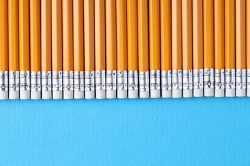 Many pencils on light blue background, top view. Space for text