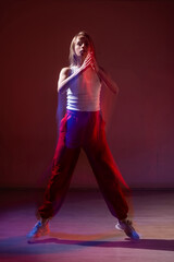 A young woman dances contemporary dances in blue and red light. Long exposure. Vertical photo. 