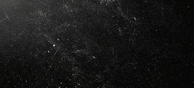 Dark grunge paper texture with distressed, scratched surface and white dust particles. Retro vintage style black background with subtle imperfections