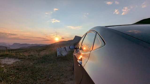 A sleek, beautiful car truly captures the stunning beauty of a mesmerizing sunset in a serene, picturesque landscape