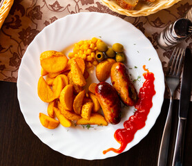 Roasted sausages served with baked potatoes and corn on white plate. High quality photo