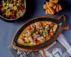 Grilled calamari with cherry tomatoes and herbs, served on a hot plate with sauce for an elegant Mediterranean seafood presentation