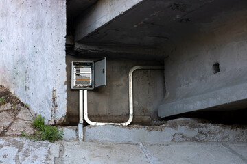 An open electrical panel on the concrete wall under the bridge.