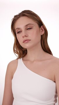 Beautiful woman in white top, blonde hair and neat makeup poses for the camera. Beauty face.