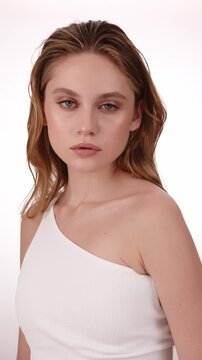 Beautiful woman in white top, blonde hair and neat makeup poses for the camera. Beauty face.