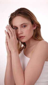 Beautiful woman in white top, blonde hair and neat makeup poses for the camera. Beauty face.