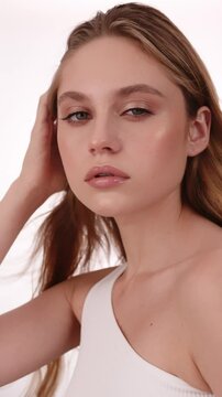 Beautiful woman in white top, blonde hair and neat makeup poses for the camera. Beauty face.