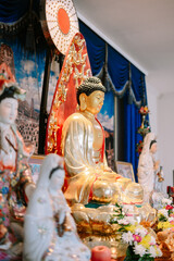 Golden buddha statue amidst ornate religious adornments in a temple