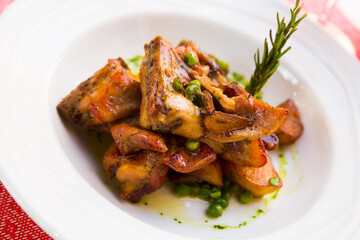 Tasty rabbit meat with garlic served with potatoes and peas on plate