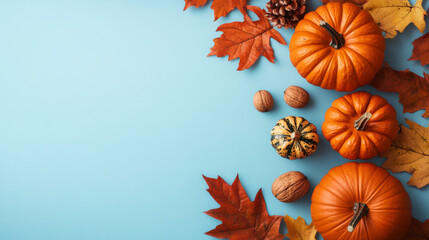 Flat lay autumn composition with bright orange pumpkins, dried maple leaves, and pinecones on a blue background, perfect for fall, Thanksgiving, or seasonal decoration themes.