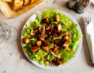 Lettuce, crouton, lardon French salad served on plate.