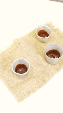 Poniendo la mezcla para hacer flan en los potes de aluminio. Preparaci&oacute;n de postre, cocina casera. Footage de postres, flan, cocina casera 