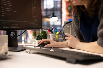 Female developer coding cloud computing applications on pc in a modern tech workspace. Woman IT...