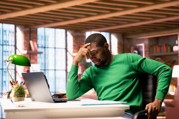 Remote employee at home office desk waiting for laptop operating system to open, feeling bored....