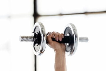 Exercise with dumbbells. Female hand holding sports equipment for training for biceps at gym or home, close up, copy space