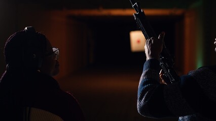 Man holds rifle, enjoying recreational shooting experience in firing range next to group of...