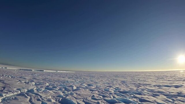 Massive tabular iceberg drifting among pack ice, casting dramatic shadows under low polar sunlight across expansive Antarctic seascape with pristine frozen ocean stretching toward distant horizon