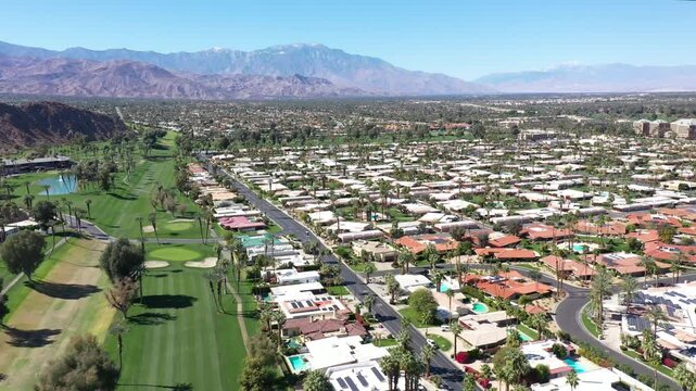 Aerial view of a luxury and upscale neighborhood with a golf course and mountains in the Palm Springs area of California.
