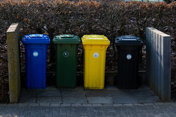 Colorful waste bins lined up along a pathway in a quiet area