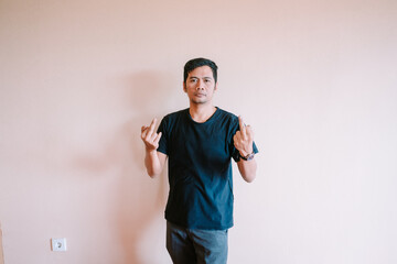 Defiant man showing middle fingers against plain backdrop in studio