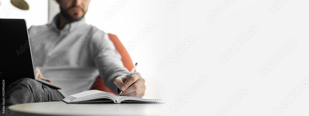 Aufkleber Close up of focused business man sitting at desk working using pc taking notes in notebook at office, selective focus on hand holding pen in foreground, blurred background. Studying online